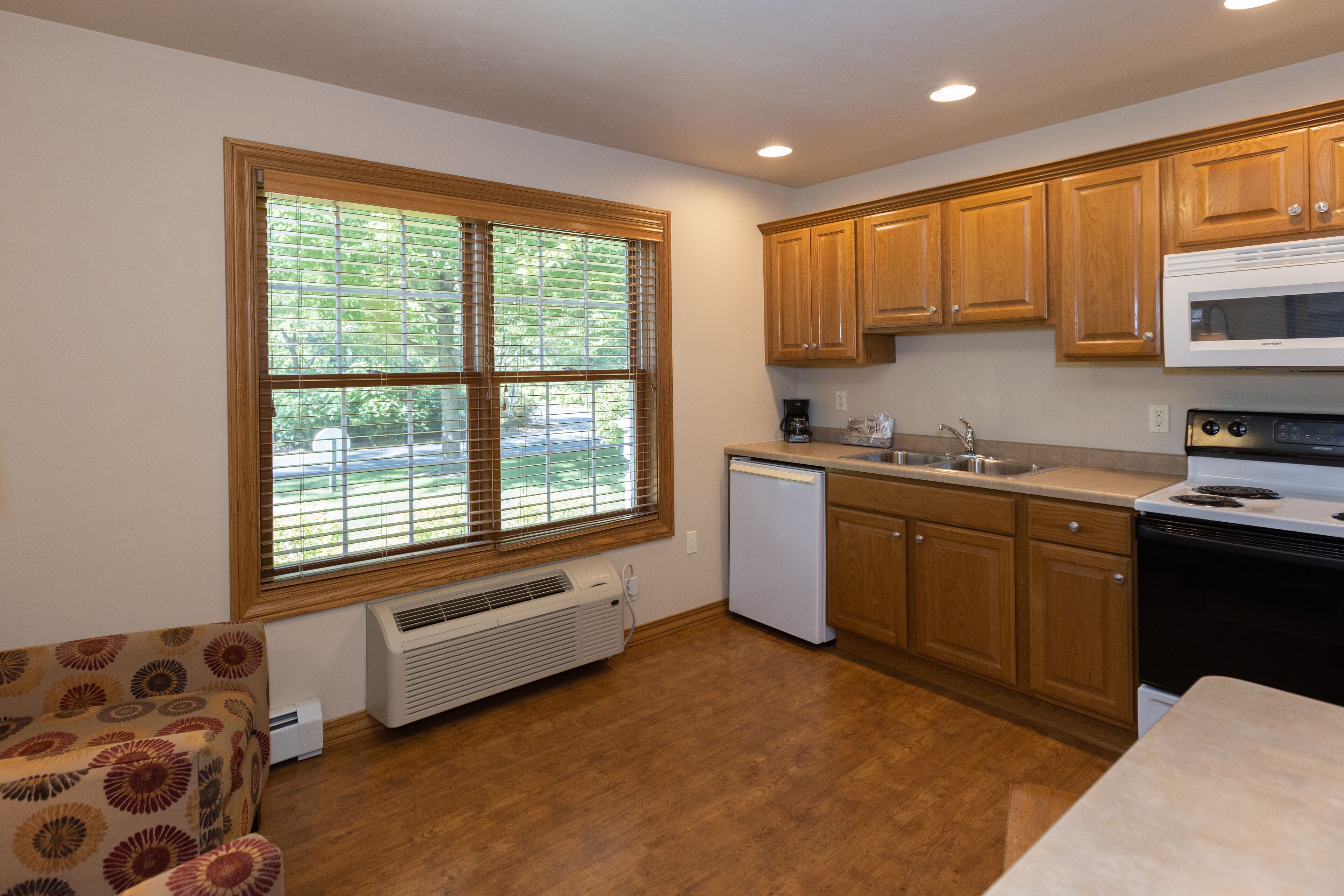 A compact kitchen with wooden cabinets, a built-in microwave, and a dishwasher.
