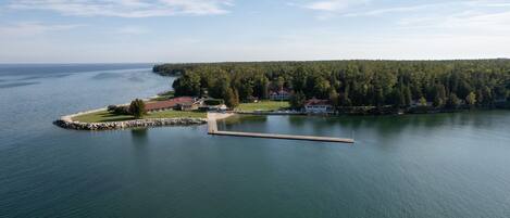 A lakeside property with a dock, a grassy area, and a building with a red roof.