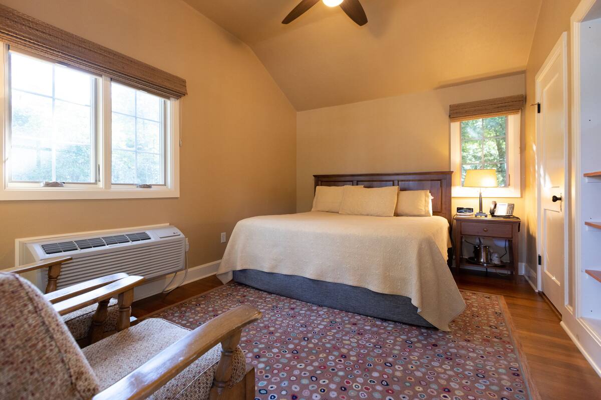A bedroom with a bed, a desk, and a chair.