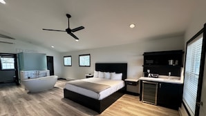 Un dormitorio moderno con una cama grande, un baño privado y una kitchenette.