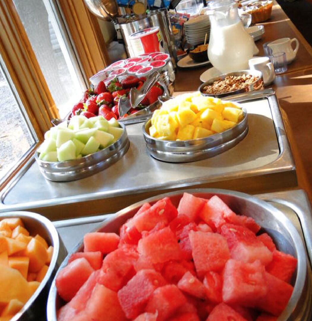 A buffet with various fruits and a pitcher of milk.