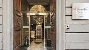 An entrance to The Independent Hotel in Rome with a modern elevator and a sign indicating its name and location. - The Independent Hotel (Rome)
