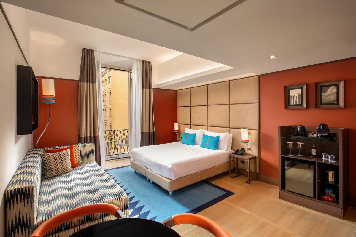 A hotel room with a bed, sofa, and a TV.