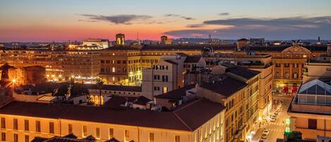 A cityscape at dusk with illuminated buildings and a prominent dome structure.