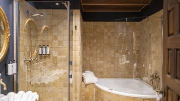 A luxurious bathroom with a freestanding bathtub, a glass-enclosed shower, and a marble-tiled wall.