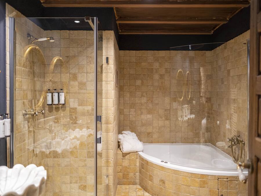 A luxurious bathroom with a freestanding bathtub, a glass-enclosed shower, and a marble-tiled wall.