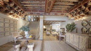 A spacious interior with a high ceiling, exposed brickwork, and a staircase leading to an upper level.