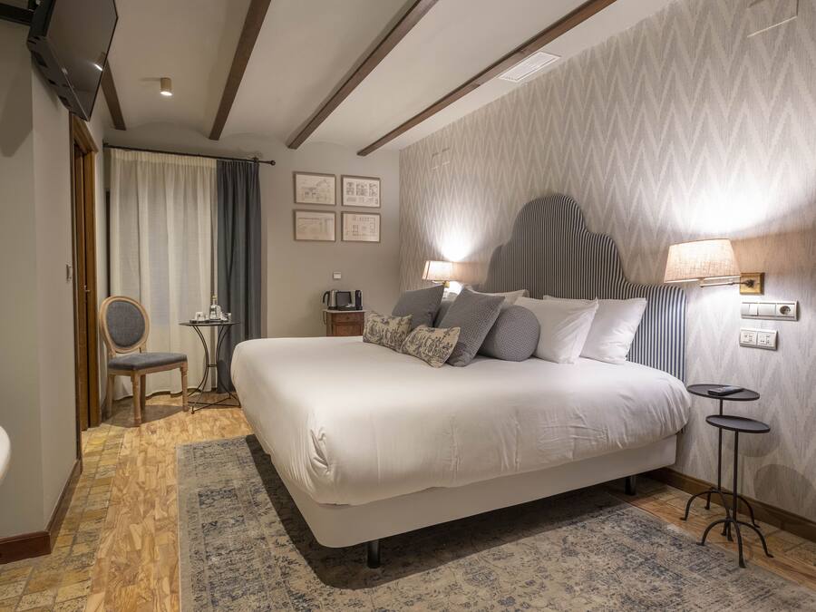 Una habitación de hotel moderna con una cama grande, una mesita auxiliar, una silla y un escritorio con una lámpara.