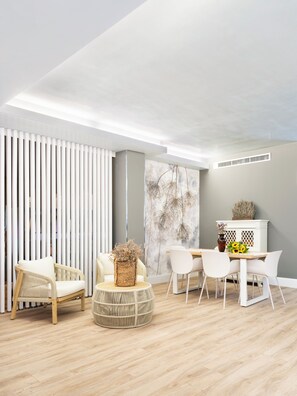 A modern living room with a dining area, featuring a white sofa, wicker ottoman, and a dining table with chairs. - Hotel Ca' Tron (Dolo)