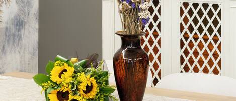 A table with a vase of sunflowers and a decorative arrangement of dried flowers.