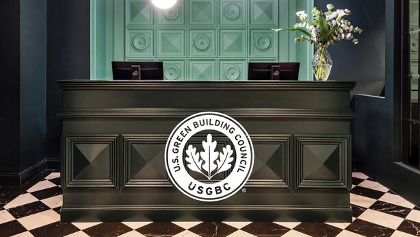 A reception desk with a U.S. Green Building Council logo, a vase with white flowers, and a checkered floor.