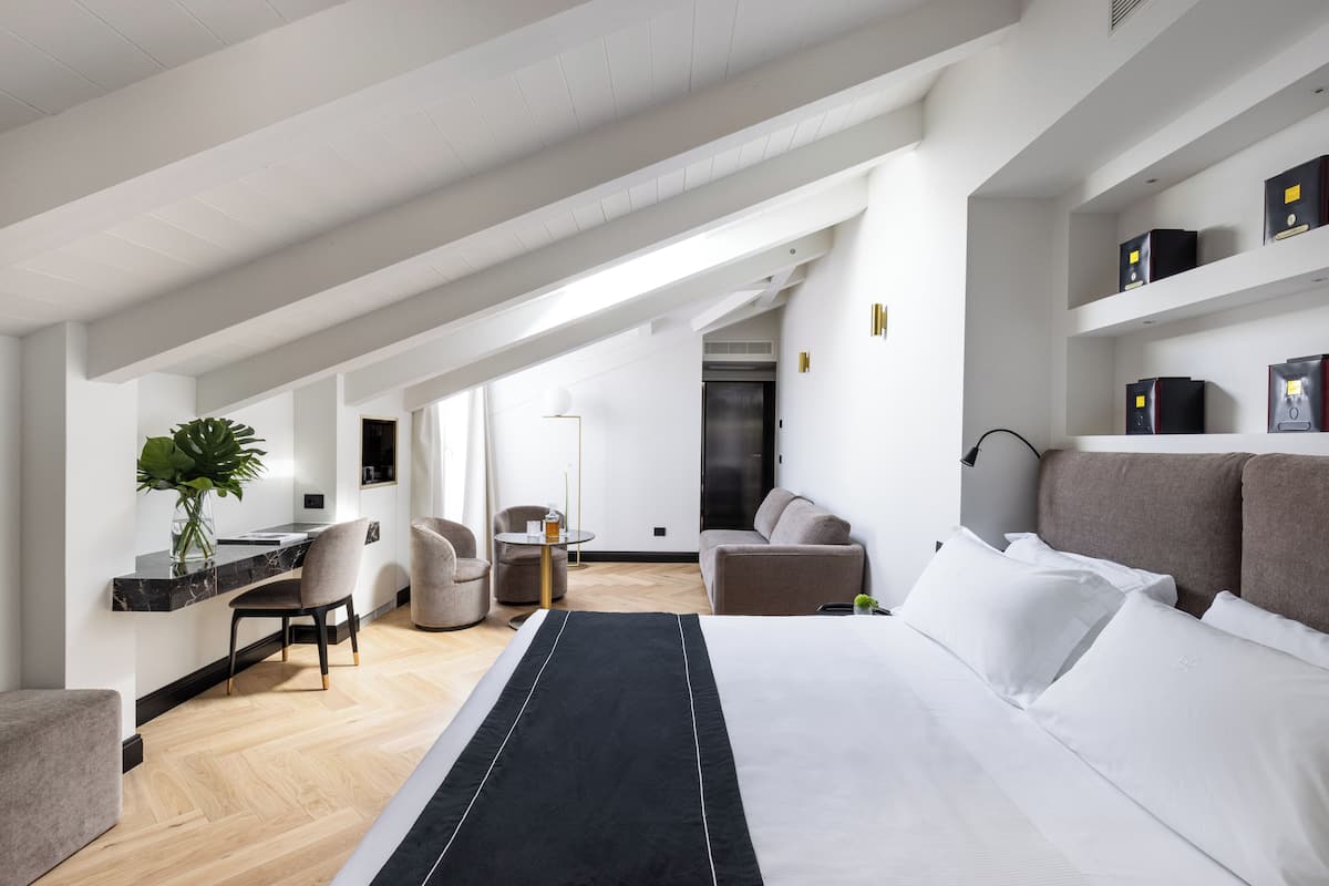 Una habitación de hotel moderna con una cama grande, un escritorio, una silla, un sofá y una mesita.