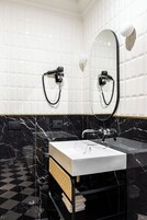 Un bagno con un lavandino bianco, piastrelle di marmo nero e un pavimento a scacchi.