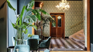 A lobby with a checkered floor, a chandelier, and a staircase.