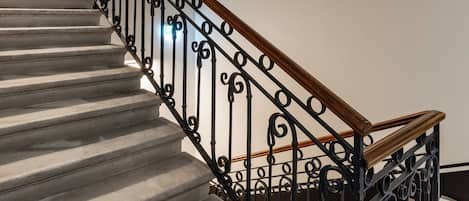A staircase with a black metal railing and wooden handrail, leading to an upper floor.