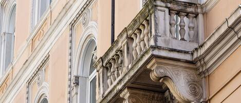Fachada de edificio con detalles arquitectónicos ornamentales, incluyendo ventanas en arco y trabajos de cantería decorativos.