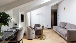 A modern living room with a dining table, two armchairs, a sofa, and a large plant.
