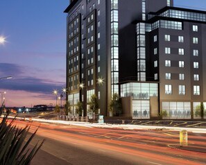 A modern multi-story building with a prominent glass facade, a flat roof, and a series of balconies. - Leonardo Hotel Nottingham  (Nottingham)
