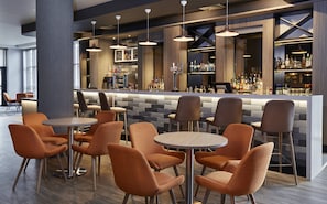 A bar area with multiple seating options, a bar counter with a variety of bottles, and pendant lighting. - Leonardo Hotel Nottingham  (Nottingham)