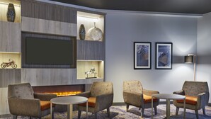 A modern lounge area with seating, a fireplace, and decorative items on shelves.