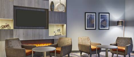 A modern lounge area with seating, a fireplace, and decorative items on shelves.