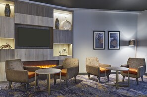 A modern lounge area with seating, a fireplace, and decorative items on shelves.