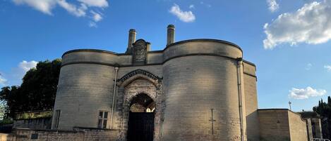A historic stone building with a central arched entrance and two cylindrical towers.