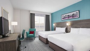 A hotel room with two beds, a desk with a TV, a chair, and a window with curtains. - Leonardo Hotel Nottingham  (Nottingham)