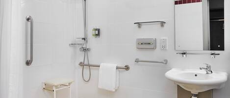 A modern bathroom with a shower, grab bars, a sink, and a toilet.