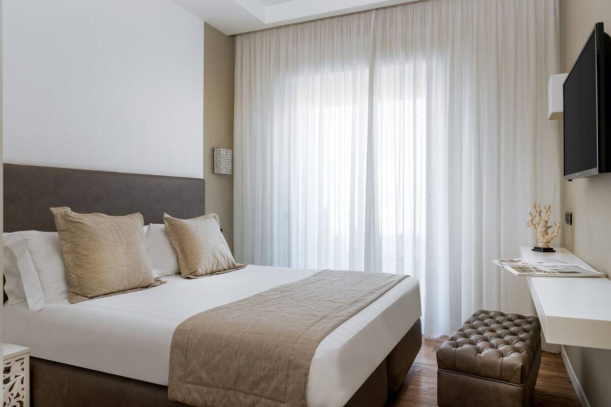 A hotel room with a large bed, a desk, and a television.