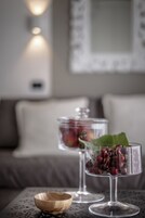A table with a glass bowl and two glasses containing cherries, set on a patterned tablecloth.