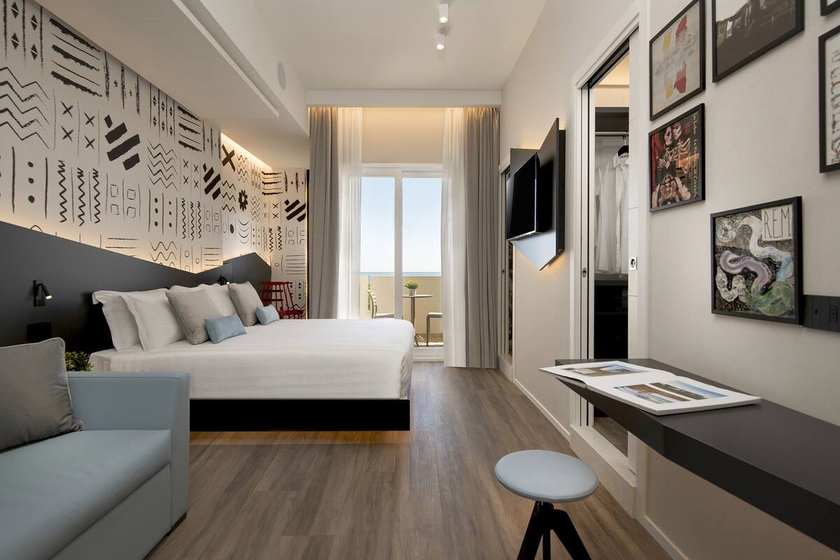 A modern bedroom with a large bed, a desk, and a TV.