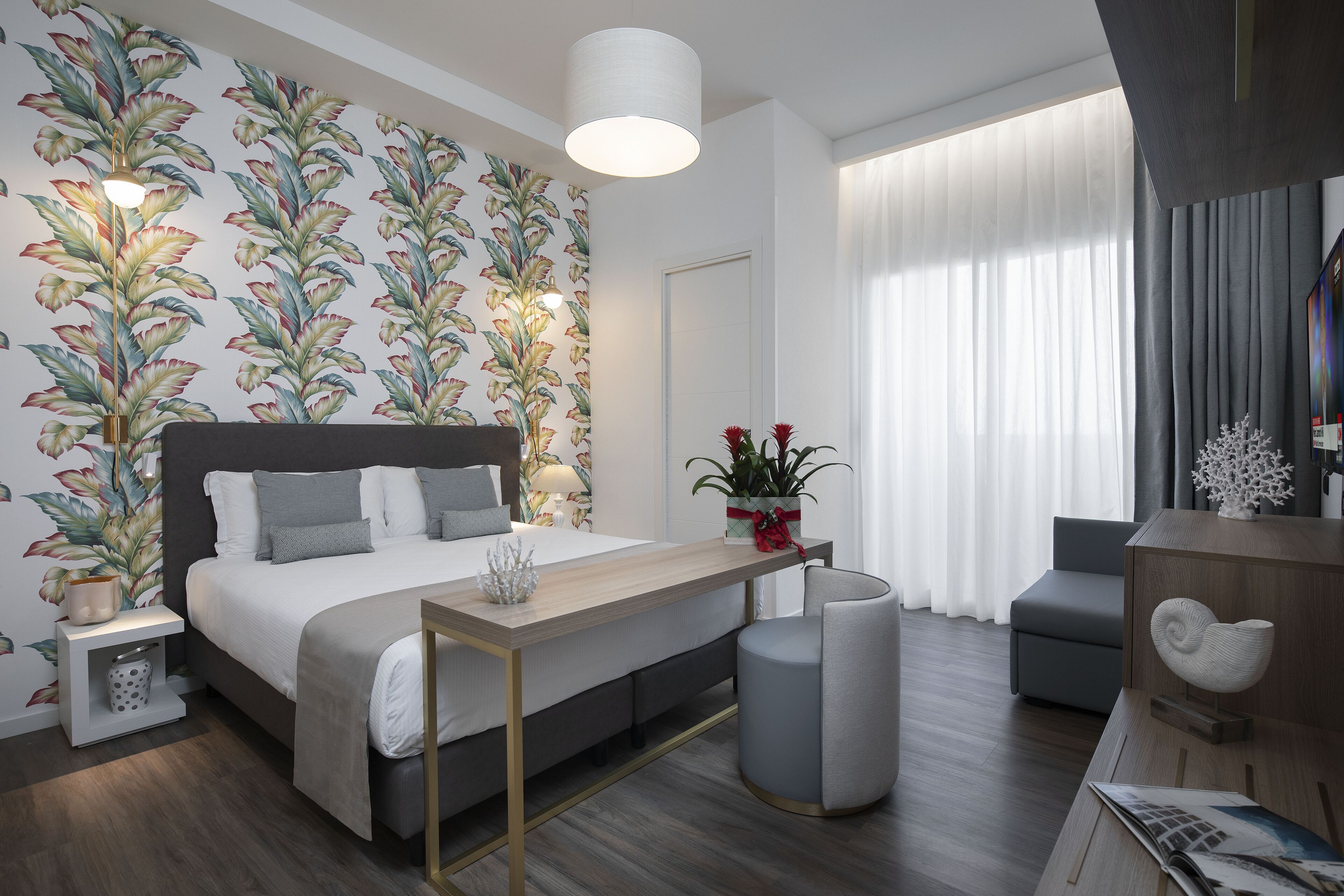 Quarto moderno com uma cama grande, mesas de cabeceira, escrivaninha e uma cadeira.