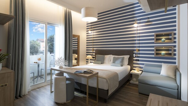 Un dormitorio moderno con una cama grande, mesitas de noche, un sofá y vistas al exterior.