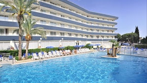Een hotel met een zwembad, meerdere balkons en ligbedden.