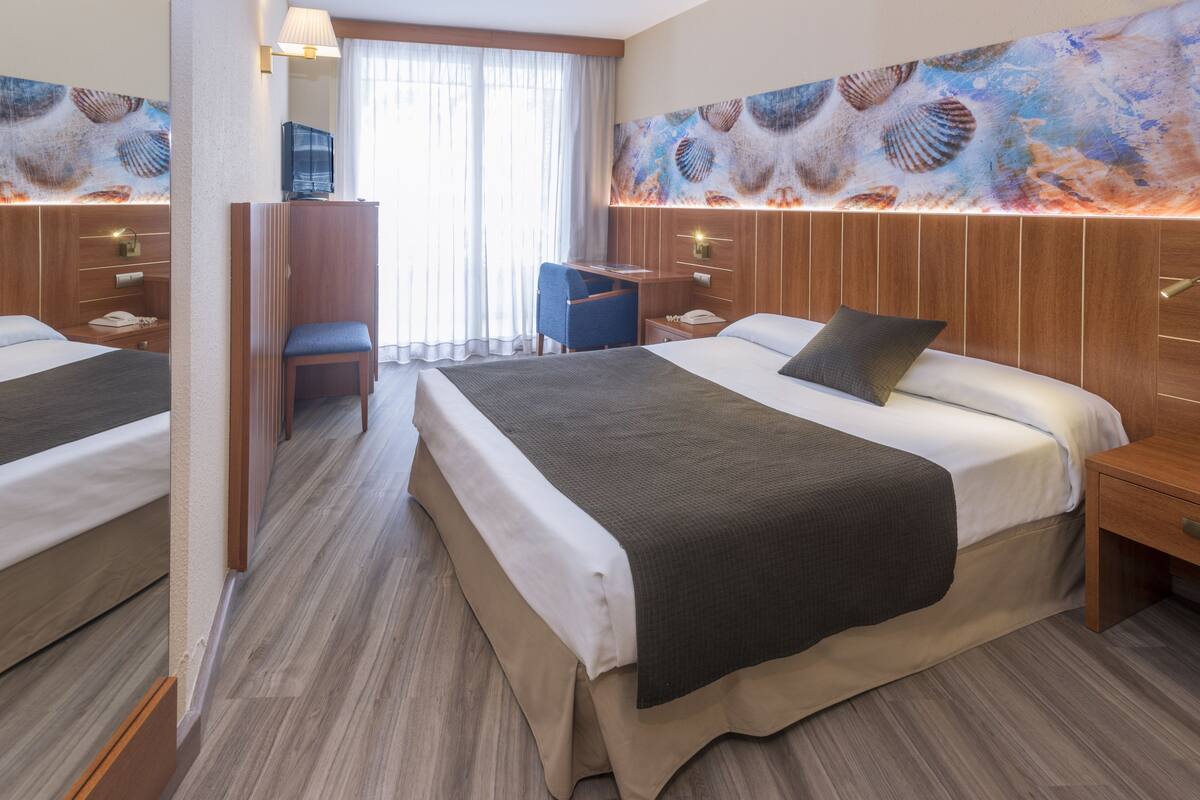 Een hotelkamer met twee bedden, een bureau, een stoel en een televisie.