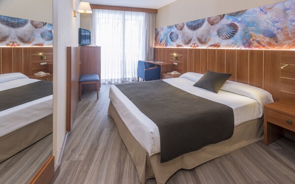 Habitación de hotel con dos camas, un escritorio, una silla y una obra de arte grande en la pared.