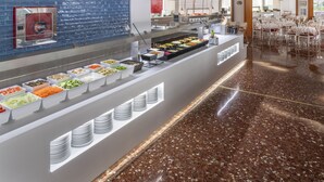 Een buffetgedeelte met verschillende food stations en een zithoek met witte stoelen.