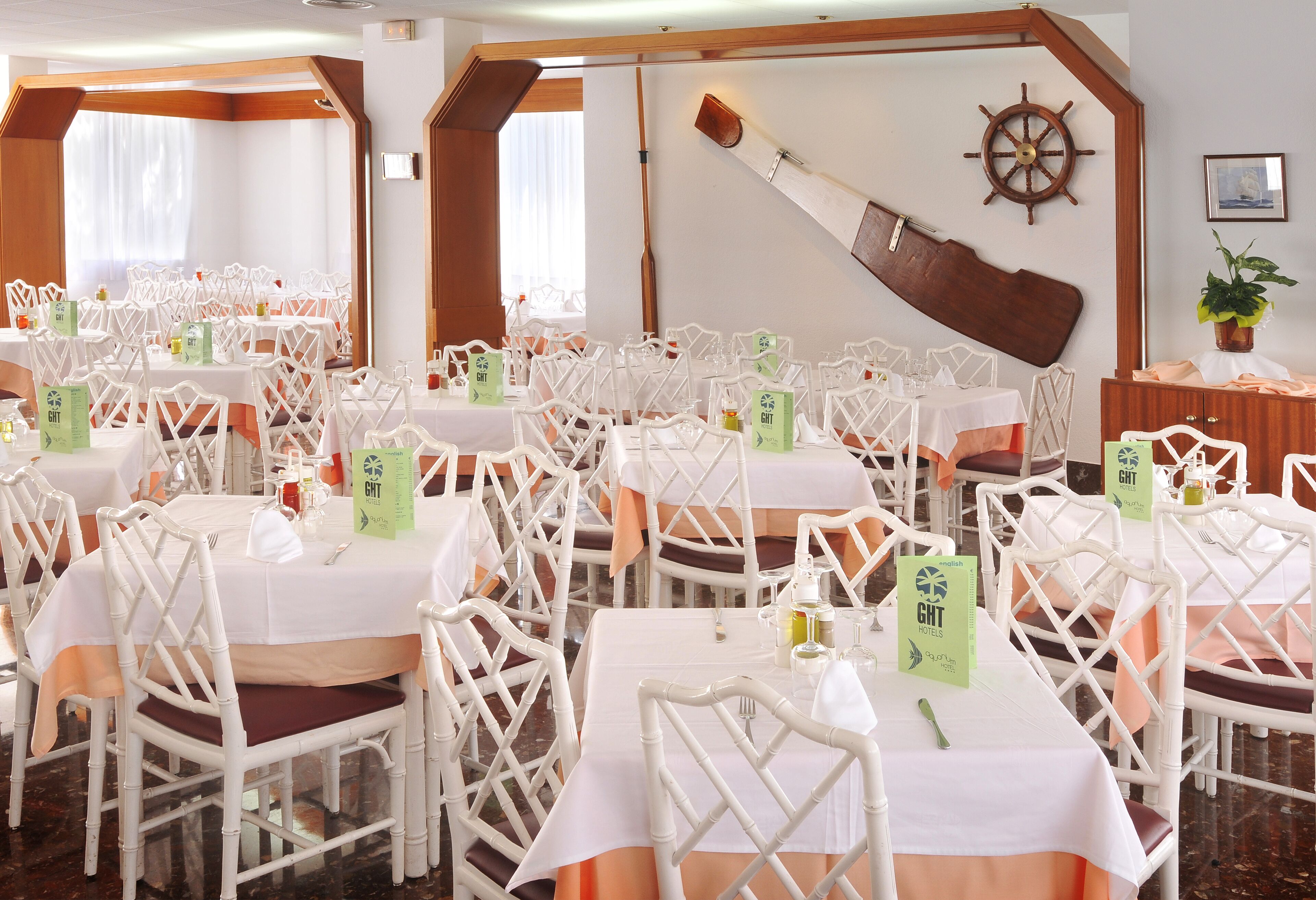 A banquet hall with white chairs and tables, each with a green 'GHT' sign.