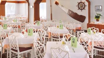 A banquet hall with white chairs and tables, each with a green 'GHT' sign.