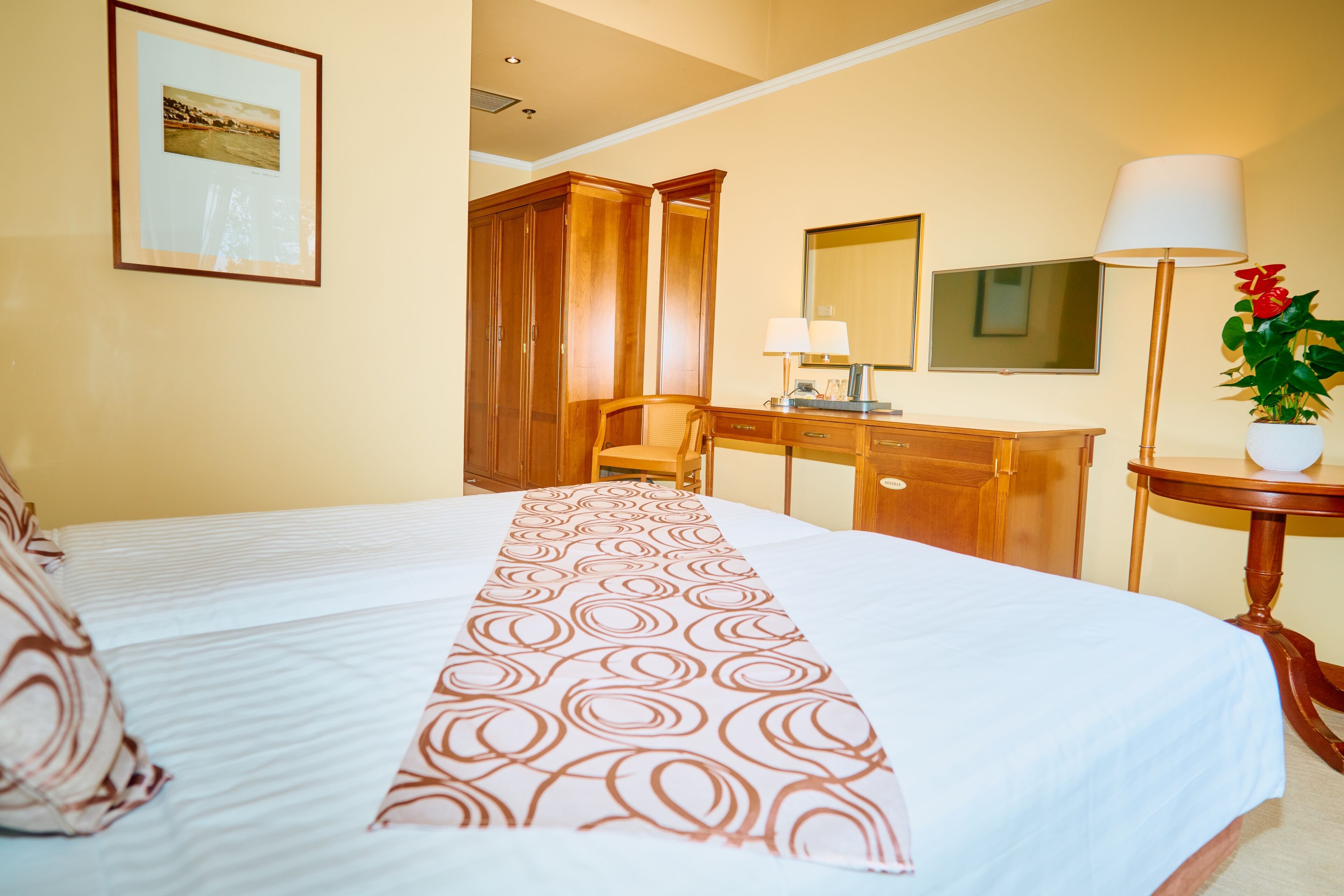 Ein Hotelzimmer mit einem großen Bett, einem Holztisch, einem Stuhl, einem Spiegel und einer Lampe.