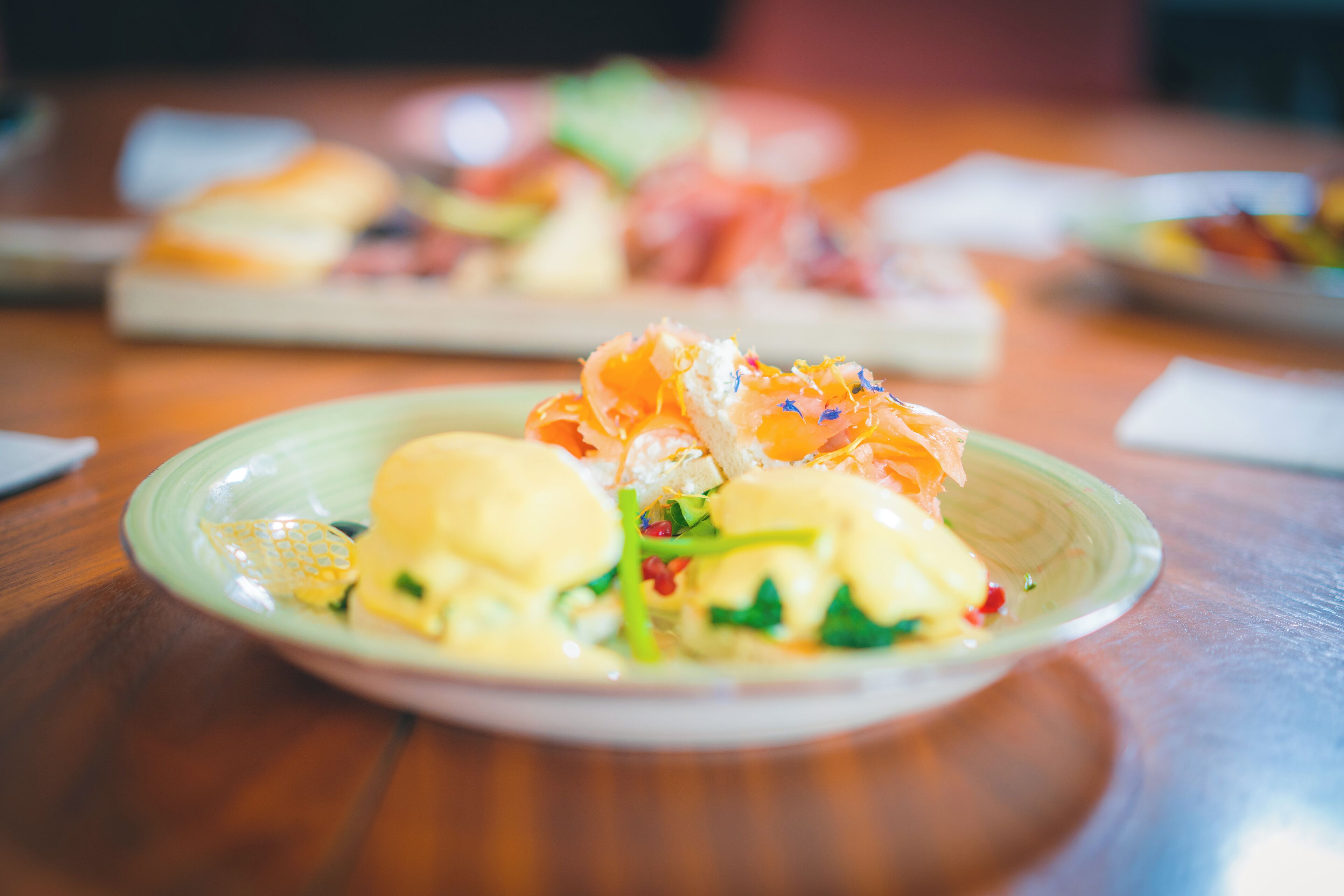 Ein Teller mit Essen, darunter Lachs und grünes Gemüse auf einer Holztischplatte.