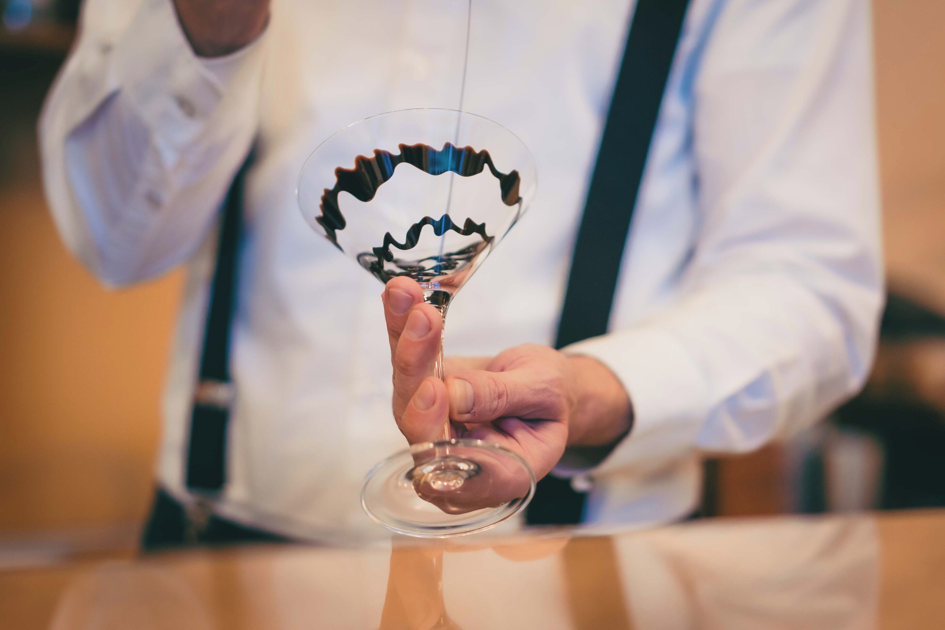 A person holding a wine glass with a unique, wavy design.