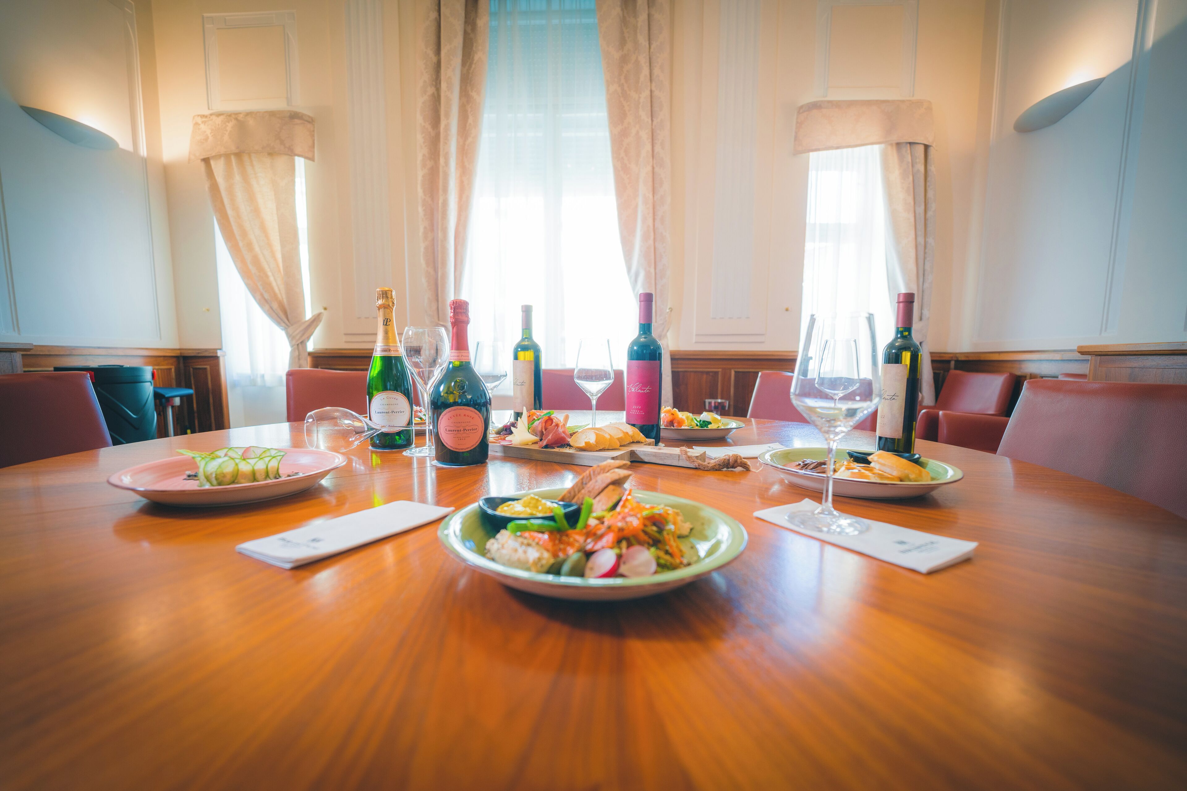 Een eettafel met borden eten, flessen wijn en glazen.