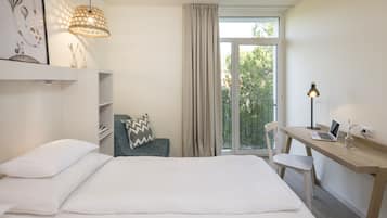 Ein modernes Hotelzimmer mit einem Bett, einem Schreibtisch mit Laptop, einem Stuhl, einer Lampe und einem fenster mit Vorhängen.