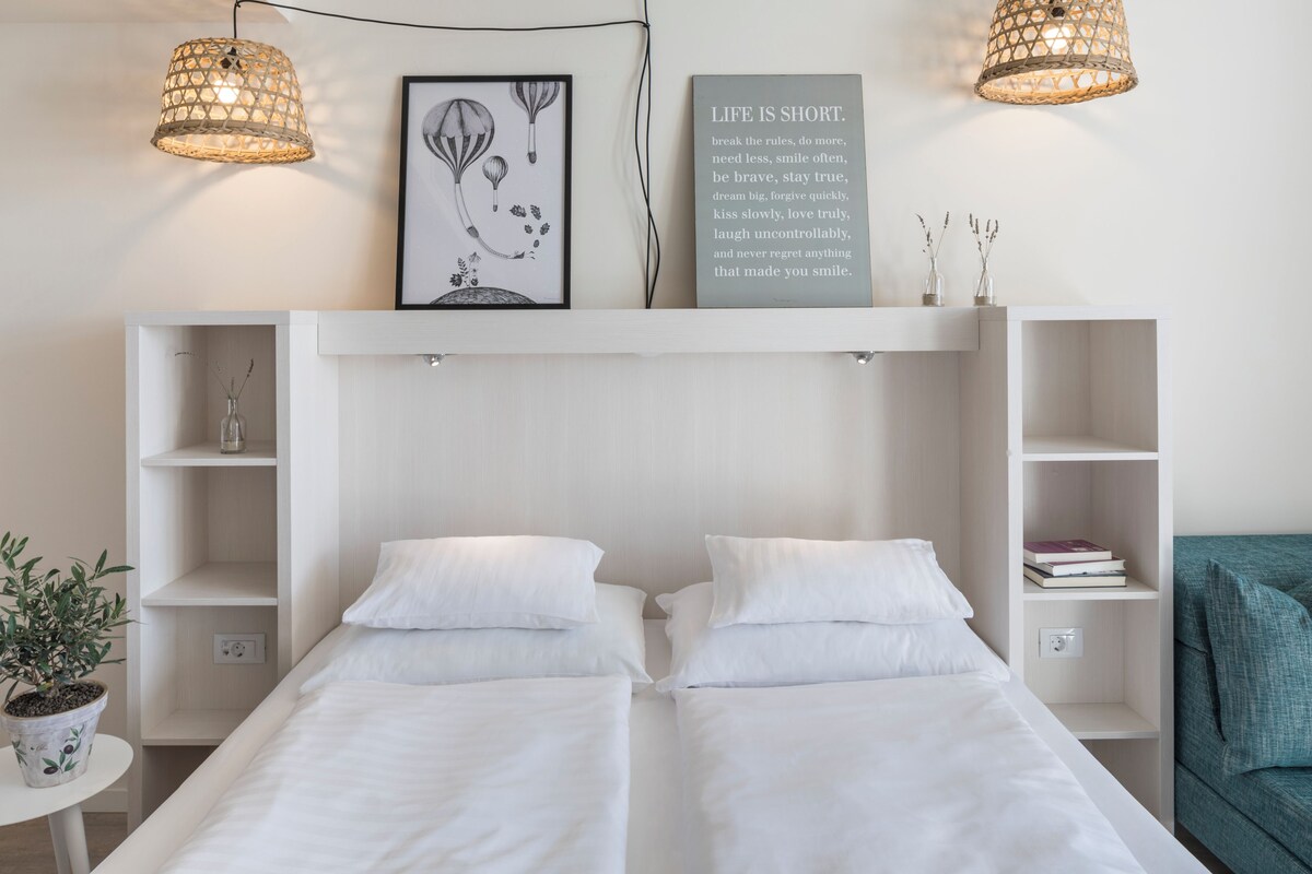 Un dormitorio moderno con dos camas individuales, una obra de arte enmarcada grande, una frase motivadora y estanterías empotradas.