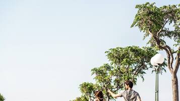 Un couple fait du jogging sur un chemin pavé, avec des arbres et un lampadaire en arrière-plan.