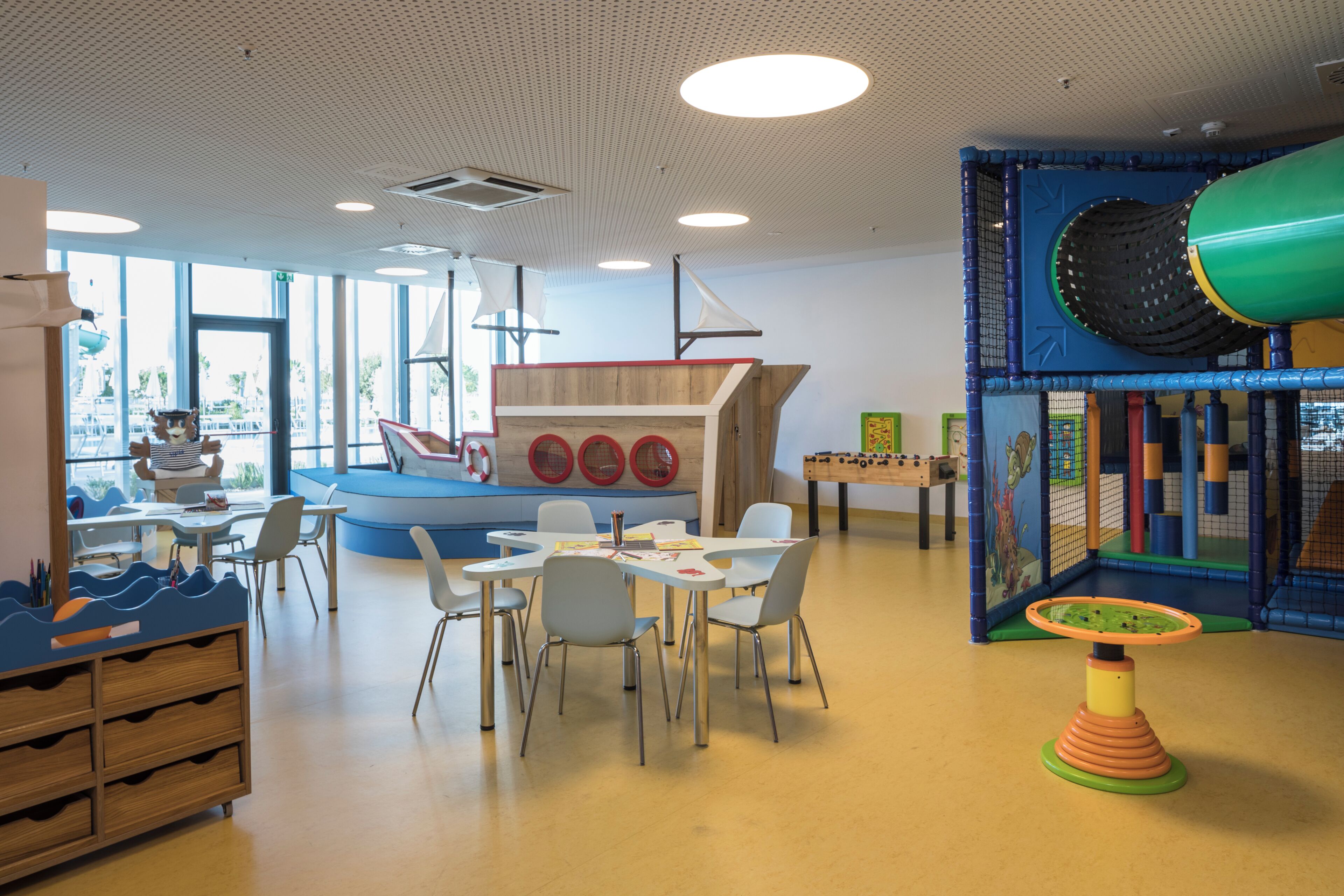 Un área de juegos infantiles con mesas, sillas y una estructura para jugar.