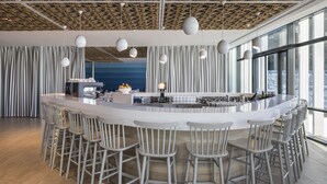 A modern bar area with a round counter, multiple stools, and pendant lighting.