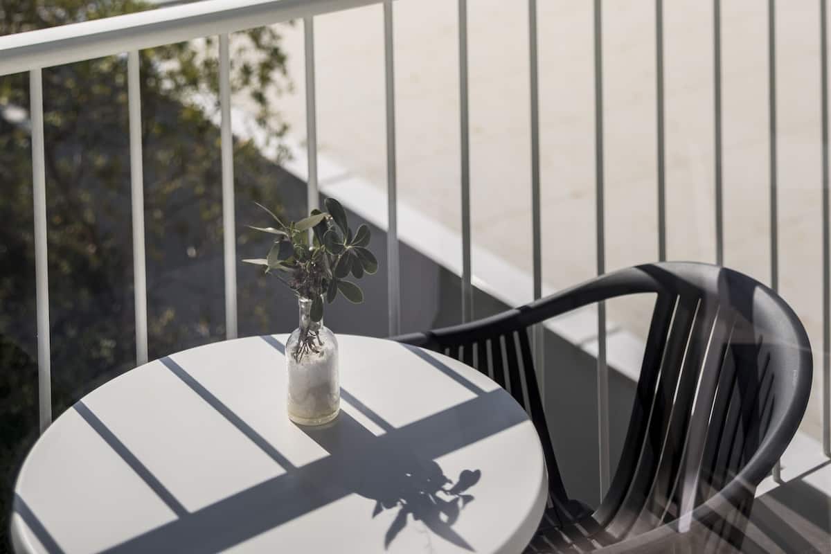 A balcony with a table and chairs, overlooking a pool area with umbrellas and lounge chairs.
